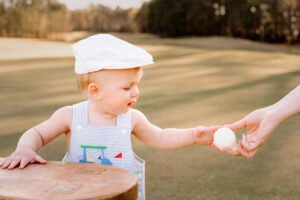 Family Photographer, young boy being handed a golf ball on golf course