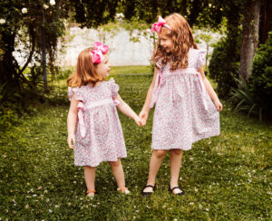 Family Photographer, two sisters walking hand-in-hand in garden