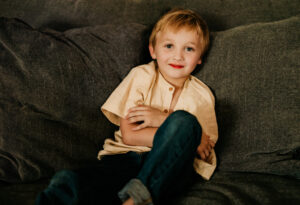 Family photographer, boy lying on brown couch