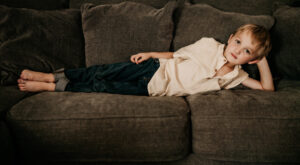 Family photographer, boy lying on brown couch