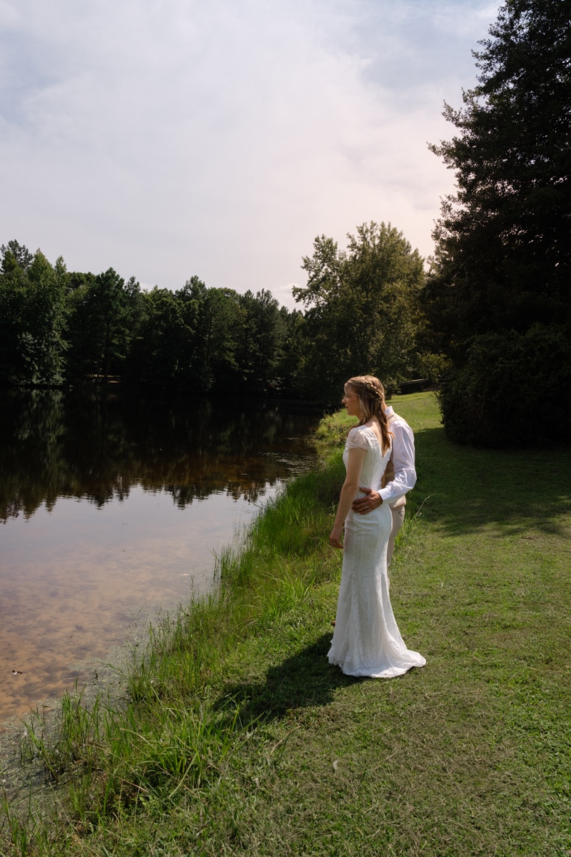 Wedding Photographer, groom holding bride at waist overlooking river