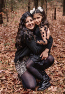 Family photographer, mother holding child kneeling in woods