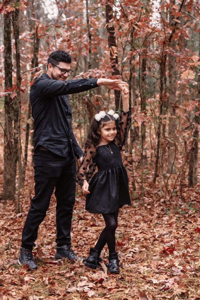 Family photographer, father twirling daughter, dancing in woods